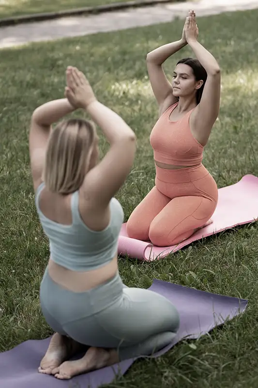 2 Frauen mit etwas molliger Figur machen Yoga für Dicke